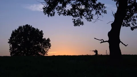 Man with a gun walks against the background of the sunrise 4k Видео 80314001