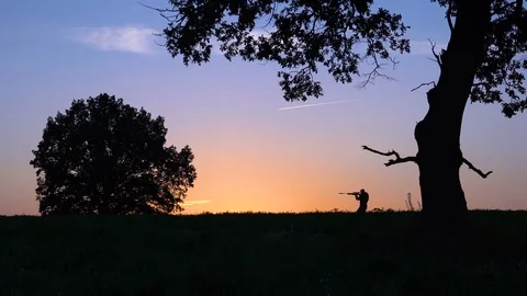 Man with a gun walks against the background of the sunrise slow Video stock 80315335