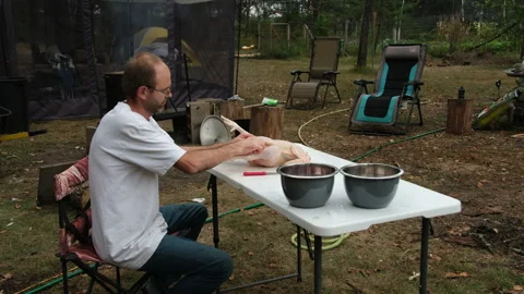 Man gutting or processing his own grown organic chicken in his back yard Stock Footage 250961201