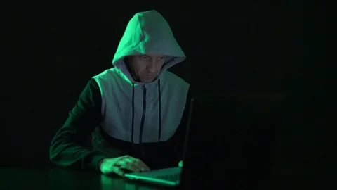 Man is a guy, a hacker in the hood, at the computer, looks at the monitor and Stock Footage 122064668