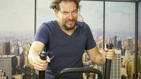 Man in gym in city getting tired working out with machine 4K slow motion trac Stock Footage