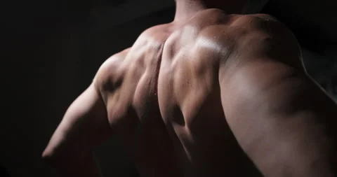 A man in the gym does an exercise by straining his back muscles.  Stock Footage 158919695
