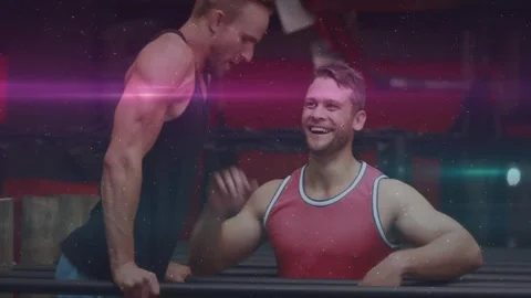 Man in gym doing L-sit, partner bracing legs, lowering and high-fiving on dip Video stock 323455857