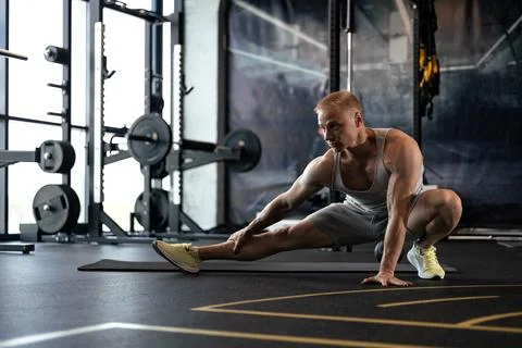 Man at the gym doing stretching exercises on the floor. Stock Photos