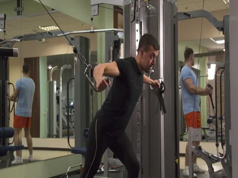 Man in gym doing weight exercise 4k video. Male training chest cable machine Stock Footage 83936153