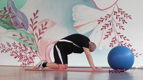 A man in a gym on a mat doing exercises to stretch the back muscles in a deflect Stock Footage 150796790