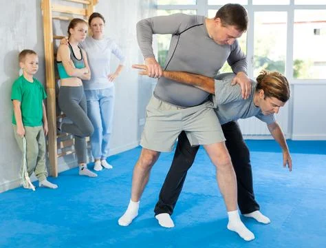 Man in gym perform basic elements of krav maga self-defense system. Stock Photos