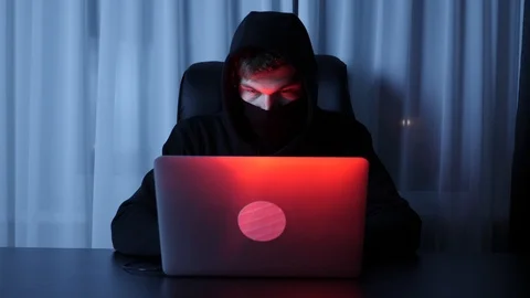 Man hacker face looking at computer screen. Male in black mask and hood breaking Video stock 125213496