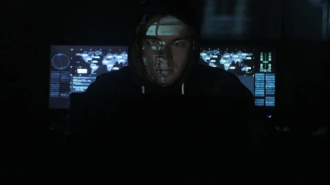 Man hacker programmer in hood working at computer while blue code characters Stock Footage 86868592