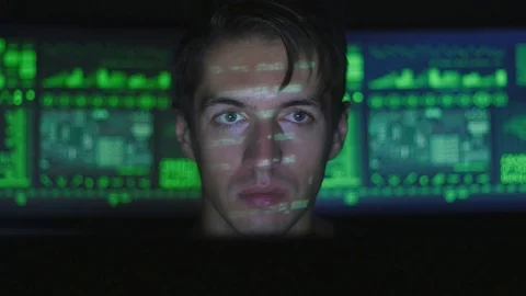 Man hacker programmer working at computer while green code characters reflect on Stock Footage 80280247