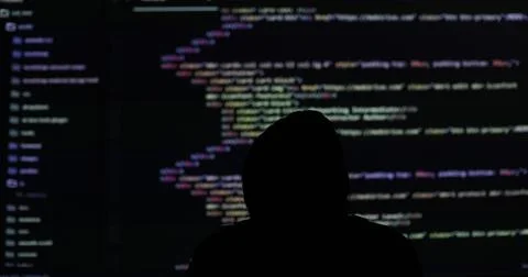 Man hacker working in dark abstract room. Programming code on a large screen in Stock Photos