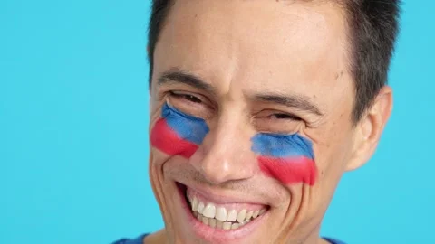 Man with a haitian flag painted on the face smiling Stock Footage 256572392