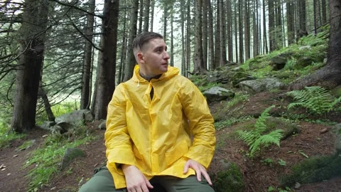 A man at a halt in the forest, gets up and puts on a backpack and walks on Stock Footage 230612392