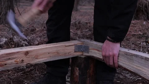 A man hammering a nail into a tree, a construction site in the woods, a buil Stock Footage 201109986