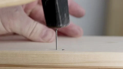 Man is hammering a nail into a wooden board. Video stock 344123737