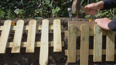 Man hammering a small fence panel into the ground. Stock Footage 89867838