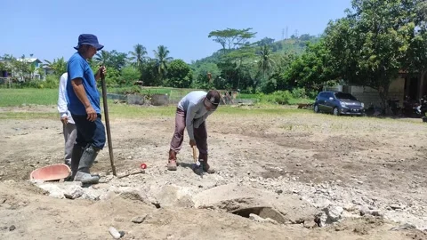 A man hammers an iron peg while his friends watch Stock Footage 236234813