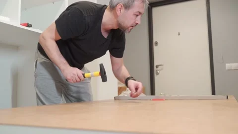 A man hammers nails with a hammer while assembling a closet. Stock Footage 171181859