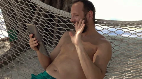 Man on hammock chatting on tablet computer lying on hammock on exotic beach, 240 스톡 동영상 59141459