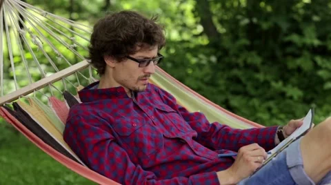 A man in a hammock drawing on paper Stock Footage 64839732