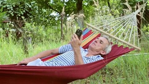 Man in a hammock playing on the phone Stock Footage 80998910