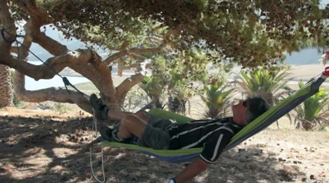 MAN IN HAMMOCK UNDER A TREE Video stock 8574948