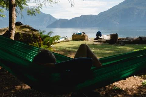 Man in hammock under trees on beach near lake Stock Photos