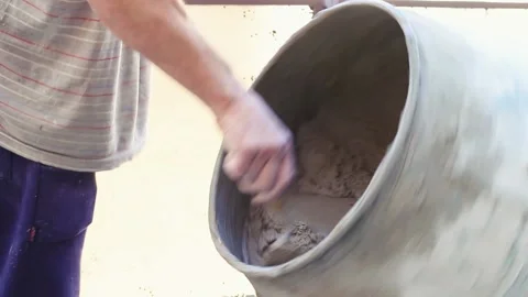 Man han with a bricklayer spoon clean the mixer machine mouth helping the mix Stock Footage 211564155