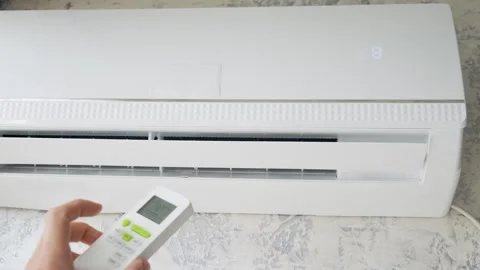 Man hand adjusting temperature on air conditioner with remote control. Man Stock Footage 244847633