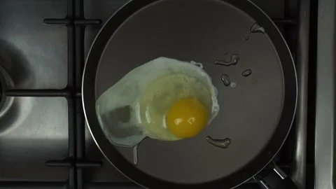 A man hand breaks an egg into a hot frying pan. Start frying. Stock Footage 150327600