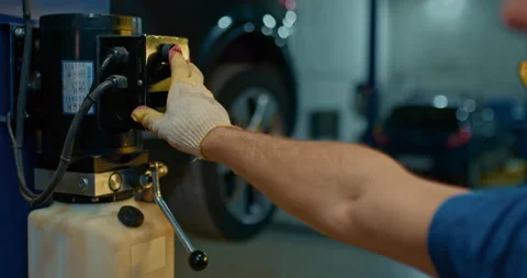 Man hand car mechanic press the switch car lift machine goes up on the lift in Video stock 224737237