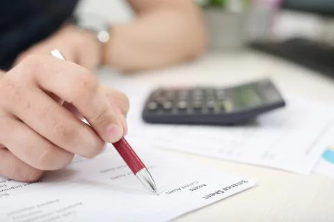Man hand is checking balance sheet with pen Foto stock