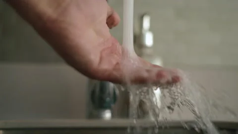 Man hand is checking the temperature of water coming out of the faucet Stock Footage 169183374