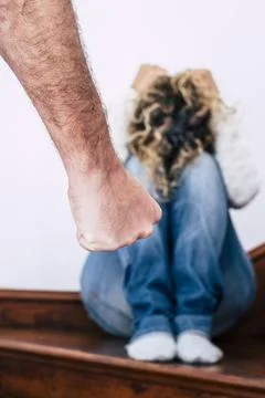Man hand close up ready to beat up his woman sitting on the ground and prot.. Fotos de archivo