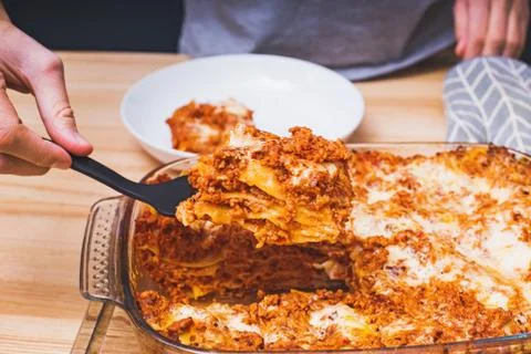 Man hand close-up taking a piece of delicious homemade lasagna Stock Photos