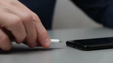 Man hand in closeup inserts a USB cable charger into mobile phone to charge it. Stock Footage 220917330