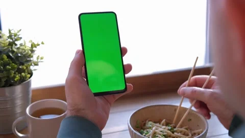 Man Hand. Cup of Hot coffee and Using Smartphone Watching Green Screen Top View Stock Footage 232600083