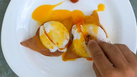 Man hand dips toasted whole wheat bread slice to fried egg yolk of sliced eggs Stock Footage 201743954