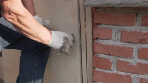 A man is hand in dirty gloves closes the door to the barn on the farm with a key Stock Footage 244830712