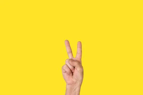 Man hand doing number two gesture on a yellow background with copy space 스톡 사진