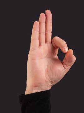 Man hand doing ok gesture on a black background with copy space Stock Photos