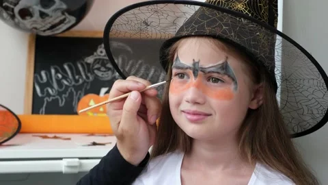 Man hand draws aqua makeup on kid girl face for Halloween party Stock Footage 211699838