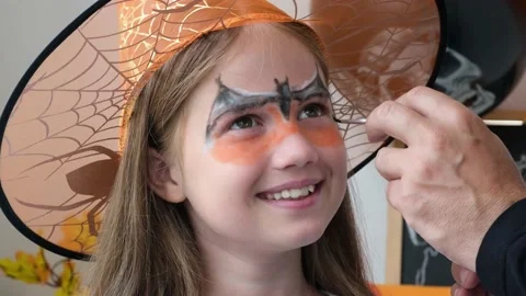 Man hand draws aqua makeup on kid girl face for Halloween party Stock-Footage 212043988