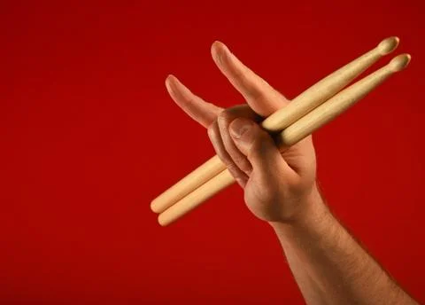 Man hand with drumsticks and devil horns over red Stock Photos