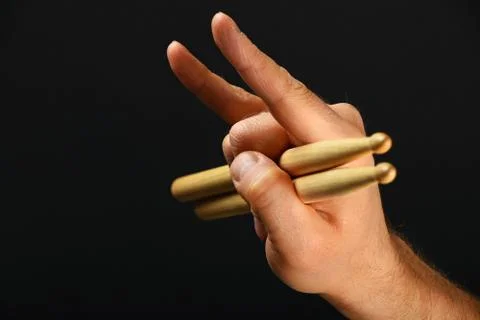 Man hand with drumsticks and devil horns over black Stock Photos