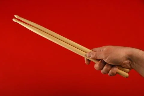 Man hand with drumsticks and devil horns over red Stock Photos