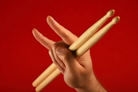 Man hand with drumsticks and devil horns over red Man hand holding two dru... Stock Photos