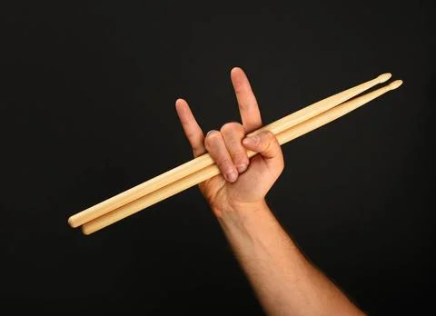 Man hand with drumsticks and devil horns over black Man hand holding two w... Stock Photos