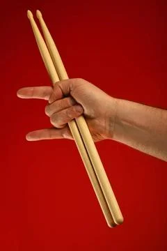 Man hand with drumsticks and devil horns over red Man hand holding two dru... Stock Photos