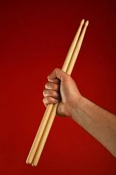 Man hand with drumsticks and devil horns over red Man hand holding two woo... Stock Photos